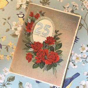 Pode incluir: Um cartão com um buquê de rosas vermelhas e o número 25 em um círculo com o texto "Happy Years". O cartão tem o texto "Congratulations on your Silver Wedding" no topo.