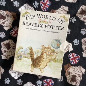 May include: A book titled "The World of Beatrix Potter" with the subtitle "The Original and Authorized Editions". The cover features a cartoon illustration of a kitten playing with a ball of yarn.