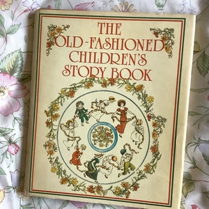 May include: The cover of a vintage children's storybook titled "The Old-Fashioned Children's Story Book". The cover features a colorful illustration of children dancing in a circle around a floral wreath.