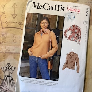 May include: McCall's sewing pattern featuring a woman wearing a rust-colored top and blue jeans. The pattern includes multiple view options with simple instructions. The pattern is designed and printed in the USA.