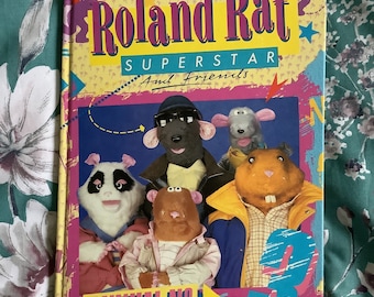 May include: A colourful book cover featuring the title "Roland Rat Superstar and Friends" with a star and the number 3. The cover features a group of cartoon characters, including a rat, a panda, and a hamster.