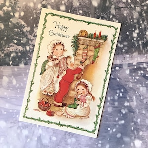 ZELDZAME vintage blanco kaart 'Happy Christmas' uit circa jaren 1970, ontworpen door Eva Harta Schattig trio van kinderen hangende kousenontwerp en lieve groet