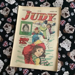 Könnte beinhalten: Ein Vintage-Comic-Cover mit einem Mädchen in einem roten Mantel und einem Schneemann. Der Comic heißt "Judy" und das Covergirl ist Helen Cope aus Slough. Der Comic ist vom 9. Januar 1980.