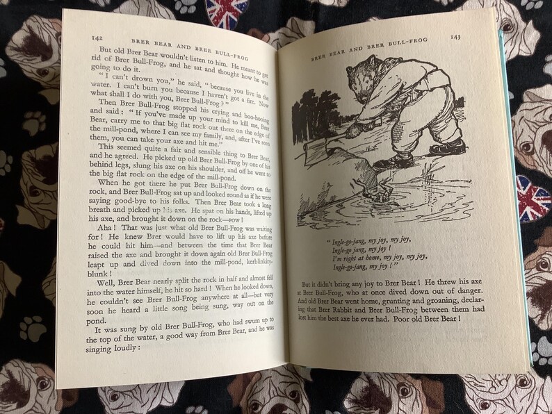 May include: Open book with illustrations and text. The left page has text about Brer Bear and Brer Bull-Frog. The right page shows an illustration of a bear with an axe. The book is open on a patterned surface.