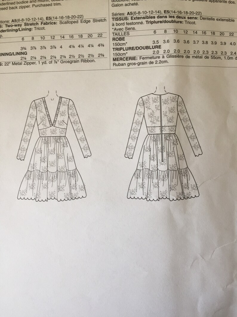 Pu&ograve; includere: Un disegno in bianco e nero di un modello di vestito con istruzioni per le taglie 6-22. Il modello include le misure per l'abito e il tessuto necessario. Il testo nell'immagine dice: "Series: A5(6-8-10-12-14), E5(14-16-18-20-22)  TISSUS: Extensibles dans les deux sens: Dentelle extensible &agrave; bord festonn&eacute;. Triplure/doublure: Tricot. "Avec Sens.  TAILLES  ROBE  150cm*  6 8 10 12 14 16 18 20 22  3.5 3.6 3.6 3.6 3.7 3.8 3.9 3.9 4.0  TRIPLURE/DOUBLURE  150cm*  2.0 2.0 2.0 2.0 2.0 2.3 2.3 2.3 2.4  MERCERIE: Fermeture &agrave; Glissi&egrave;re de m&eacute;tal de 55cm, 1.0m de Ruban gros-grain de 2.2cm."