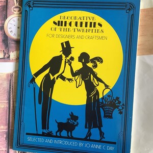 May include: A book cover with a blue background and a yellow circle featuring black silhouettes of a man, woman, and dog. The text reads "DECORATIVE SILHOUETTES OF THE TWENTIES" and "FOR DESIGNERS AND CRAFTSMEN".