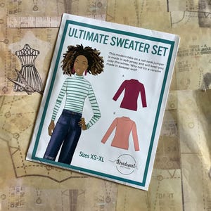 May include: A sewing pattern for a roll neck sweater set. The pattern includes instructions for making a burgundy sweater, a peach sweater, and a striped sweater. The pattern is available in sizes XS-XL. The pattern is from Threadcount Patterns.