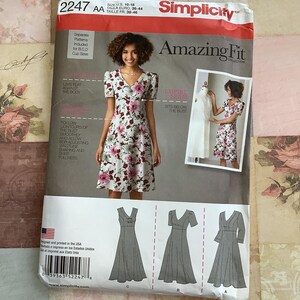 May include: Simplicity sewing pattern 2247 AA from the Amazing Fit Collection. The pattern offers various dress designs with V-necks and empire waists. The package shows a woman in a floral dress. Sizes 10-18, Euro 36-44.