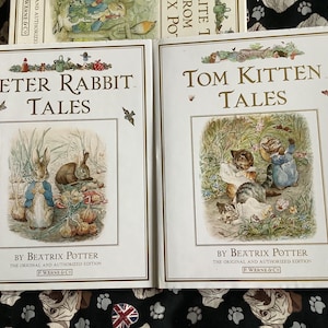 May include: Two vintage children's books with illustrated covers. The book on the left is titled "Peter Rabbit Tales" by Beatrix Potter. The book on the right is titled "Tom Kitten Tales" by Beatrix Potter.