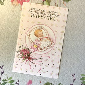 Cartão raro vintage de menina recém-nascida, por volta dos anos 80 - Bebê adorável todo aconchegado na cama, ursinho de pelúcia e lindo desenho floral - Verso doce dentro