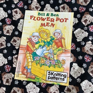 May include: A yellow and green book with the title "Bill & Ben Flower Pot Men" and the text "5 Knitting Patterns by Gary Kennedy (Stardream)". The cover features two cartoon characters holding a watering can and a flower pot.