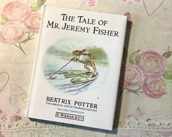 May include: A hardcover book titled "The Tale of Mr. Jeremy Fisher" by Beatrix Potter. The cover features an illustration of a frog fishing. The book is an original and authorized edition with new color reproductions.
