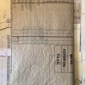 May include: A brown paper pattern with instructions for sewing a garment. The pattern is labeled "M8193 A5/F5(6-24) 0006".