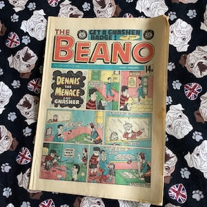Könnte beinhalten: Ein Vintage-Comic-Cover mit Dennis dem Schrecken und Gnasher. Das Cover ist gealtert und hat ein rot-weiß-blaues Farbschema. Der Titel "The Beano" ist in großen, fetten Buchstaben gedruckt. Der Comic ist aus dem März 1981.
