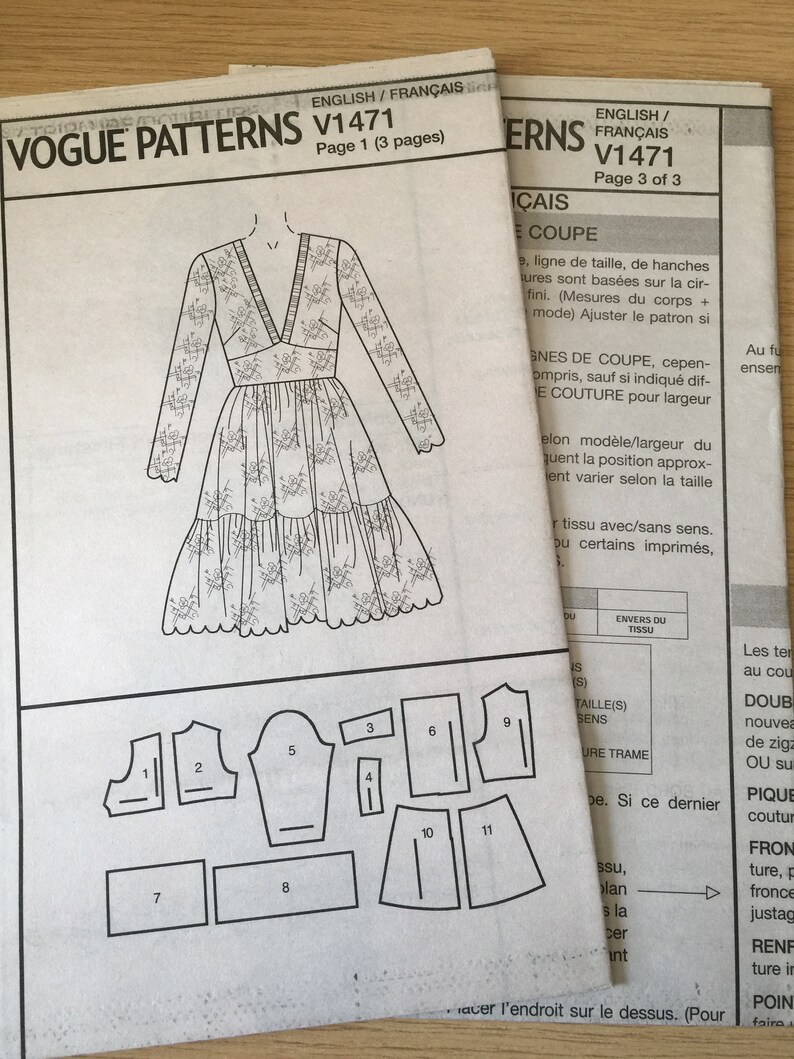 Pu&ograve; includere: Un cartamodello di cucito in bianco e nero per un abito con maniche lunghe e scollo a V. Il cartamodello comprende 11 pezzi ed &egrave; etichettato Vogue Patterns V1471.