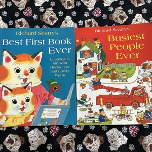 May include: Two children's books by Richard Scarry. The blue book is titled "Best First Book Ever" and features a cat illustration. The red book is titled "Busiest People Ever" and shows various characters and vehicles.