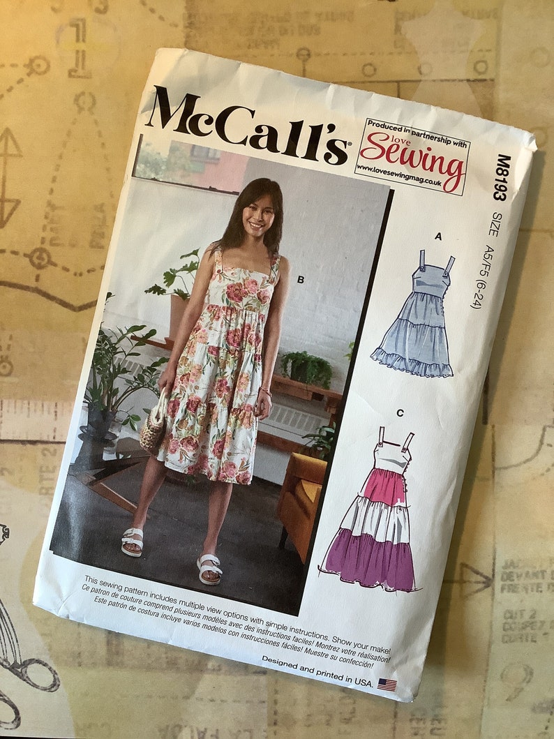 May include: McCall's sewing pattern M8193, size A5/F5 (6-24), featuring three different styles of dresses. The pattern includes simple instructions and multiple view options. The dresses are shown in a variety of colors and patterns, including floral, blue, and pink.