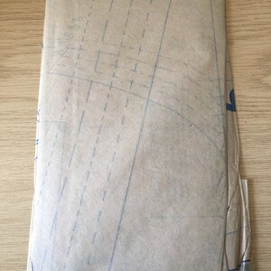 Pu&ograve; includere: Un foglio di cartamodello marrone con linee e segni blu.