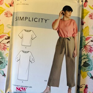 May include: A sewing pattern for a top and trousers. The pattern is for sizes XXS-XXL. The top has a round neckline and short sleeves. The trousers are wide-legged and have a tie at the waist. The pattern is from Simplicity and is easy to sew.