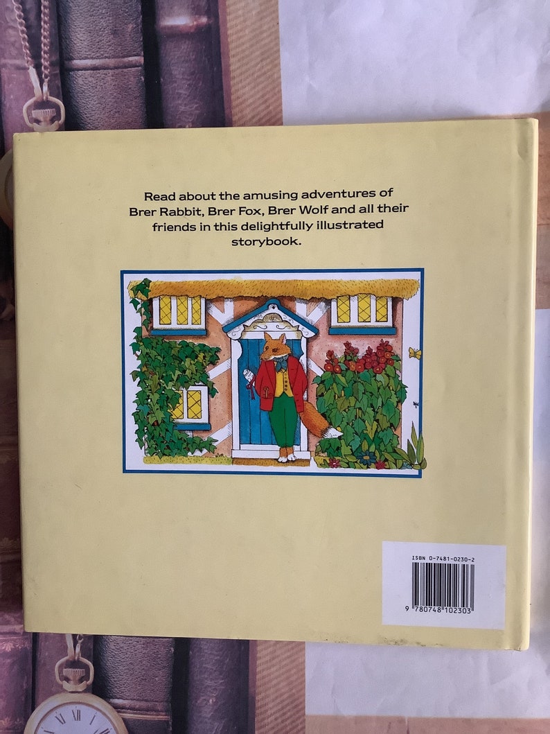 Op de afbeelding: De achterkant van een kinderboek met een cartoonvos in een rood jasje en een groene broek die voor een blauwe deur staat. Het boek is getiteld "Lees over de amusante avonturen van Brer Rabbit, Brer Fox, Brer Wolf en al hun vrienden in dit heerlijk ge&iuml;llustreerde prentenboek."