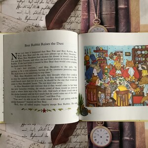 Op de afbeelding: Een vintage kinderboekillustratie die een groep bosdieren laat zien die rond een tafel in een keuken zitten. De dieren genieten samen van een maaltijd, met een verscheidenheid aan gerechten en bestek op tafel. De illustratie is in cartoon-stijl met felle kleuren en grillige details.