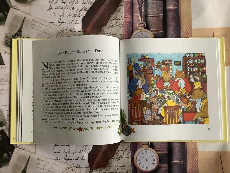 Op de afbeelding: Een vintage kinderboekillustratie die een groep bosdieren laat zien die rond een tafel in een keuken zitten. De dieren genieten samen van een maaltijd, met een verscheidenheid aan gerechten en bestek op tafel. De illustratie is in cartoon-stijl met felle kleuren en grillige details.