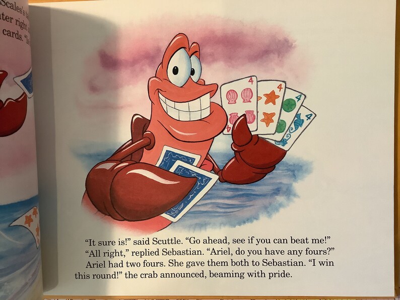 Pu&ograve; includere: Un granchio rosso con un grande sorriso tiene quattro carte da gioco nella sua chela. Le carte sono tutte quattro, con conchiglie, stelle e cerchi di diversi colori. Il testo sulla pagina dice: "Certo che s&igrave;!" disse Scuttle. "Vai avanti, vedi se riesci a battermi." "Va bene", rispose Sebastian. "Ariel, hai dei quattro?" Ariel aveva due quattro. Li diede entrambi a Sebastian. "Ho vinto questo round!" annunci&ograve; il granchio, raggiante di orgoglio.
