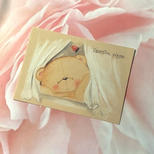 May include: A Valentine's Day card featuring a cartoon bear peeking from behind a white curtain. The bear is light brown with a red heart above it and the words "Valentine please" written on the card.
