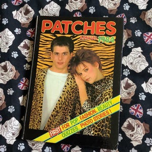 Könnte beinhalten: Ein Vintage-Magazincover mit zwei Personen in Leopardenmuster-Kleidung. Das Magazin heißt "Patches Annual 1984" und hat den Slogan "First for Pop, Fashion, Beauty, Quizzes, Photo Stories!"