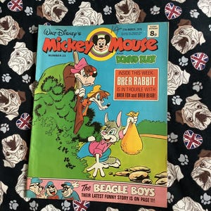 Könnte beinhalten: Ein Vintage-Comic von Mickey Mouse und Donald Duck vom 27. März 1976 mit Meister Lampe und den Panzerknackern. Das Cover zeigt farbenfrohe Illustrationen von Disney-Figuren. Der Comic liegt auf einem schwarzen Hintergrund mit Bulldoggen- und Union-Jack-Mustern.
