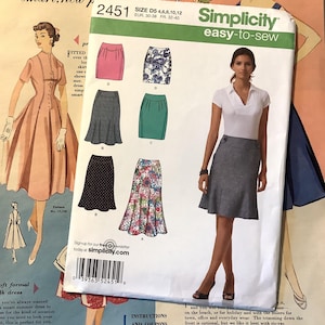 Può includere: Una busta di modello Simplicity easy-to-sew, con illustrazioni di vari modelli di gonna in rosa, floreale, verde e nero. La busta include il numero del modello 2451 e informazioni sulle taglie.