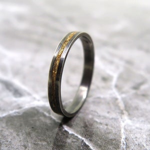 May include: A thin silver band with a gold inlay. The band is smooth and shiny.