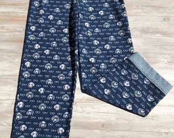 May include: Navy blue pajama pants with a repeating pattern of dogs wearing glasses. The pants have a blue and white trim at the bottom.
