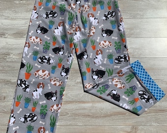 May include: Gray pajama pants with a blue and white trim. The pants have a repeating pattern of dogs and plants.