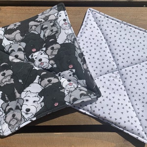 May include: Two pot holders, one with a black and white pattern of dogs and the other with a white background and a gray triangle pattern.