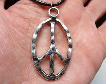 May include: A silver peace sign pendant on a black leather cord necklace.