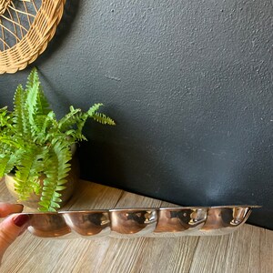May include: A silver serving tray with a scalloped edge and five indented sections. The tray is made of metal and has a shiny finish.