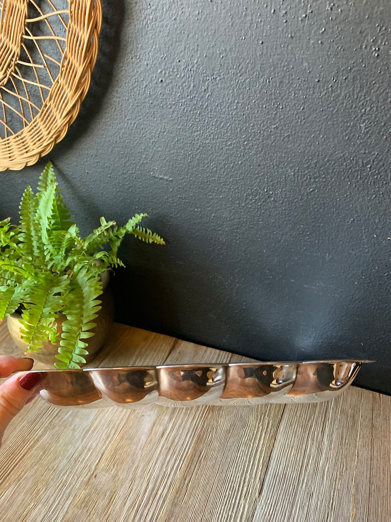 May include: A silver serving tray with a scalloped edge and five indented sections. The tray is made of metal and has a shiny finish.