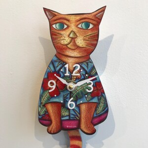 May include: Orange cat clock with a blue and red Hawaiian shirt, the clock face has white numbers and hands. The cat's tail is a pendulum.