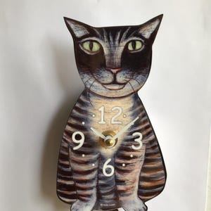 May include: A black and white striped cat clock with a white face and black numbers. The clock has a gold colored pendulum and hands.