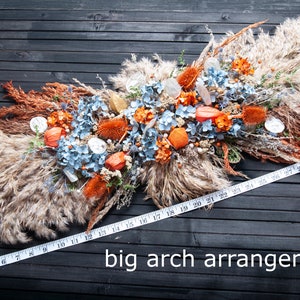 Arco de boda rústico con telón de fondo de flores secas / Decoración otoñal en tonos naranja quemado y azul grisáceo.