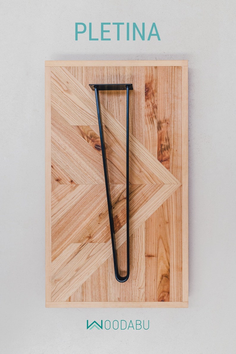 May include: A wooden table top with a geometric pattern and a black metal hairpin leg. The table top is made of light-colored wood and has a natural finish. The word "PLETINA" is written in teal at the top.