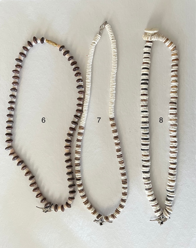 May include: Three necklaces made of brown and white beads. The necklaces are all different lengths and have different patterns. The necklaces are labeled 6, 7, and 8.
