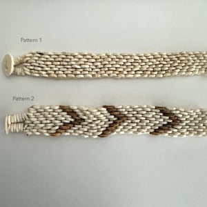 May include: Two white beaded bracelets with different patterns. The top bracelet has a simple, straight pattern. The bottom bracelet has a chevron pattern with brown beads.