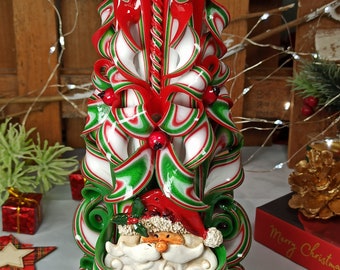 May include: A red, white, and green Christmas candle with a Santa Claus face on the bottom. The candle is decorated with holly berries and a green and white ribbon.