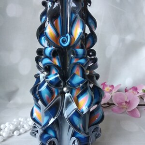Puede incluir: Una vela alta y tallada de forma intrincada con un dise&ntilde;o de espiral negro, azul, blanco y amarillo. La vela est&aacute; decorada con peque&ntilde;as cuentas plateadas.
