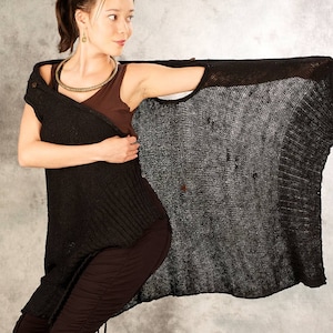 May include: A woman wearing a black knit cardigan with a brown tank top underneath. The cardigan has a loose, flowing fit and is made of a lightweight material.