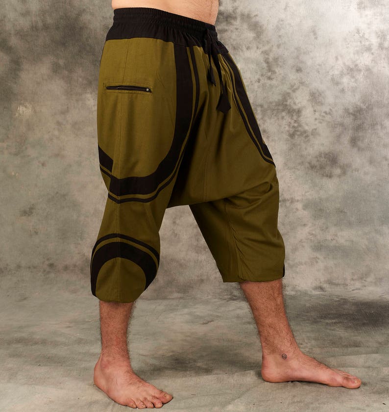 Puede incluir: Pantal&oacute;n de color verde oliva y negro con estampado, con cintura de cord&oacute;n y bolsillo con cremallera. El pantal&oacute;n es corto y de corte holgado.