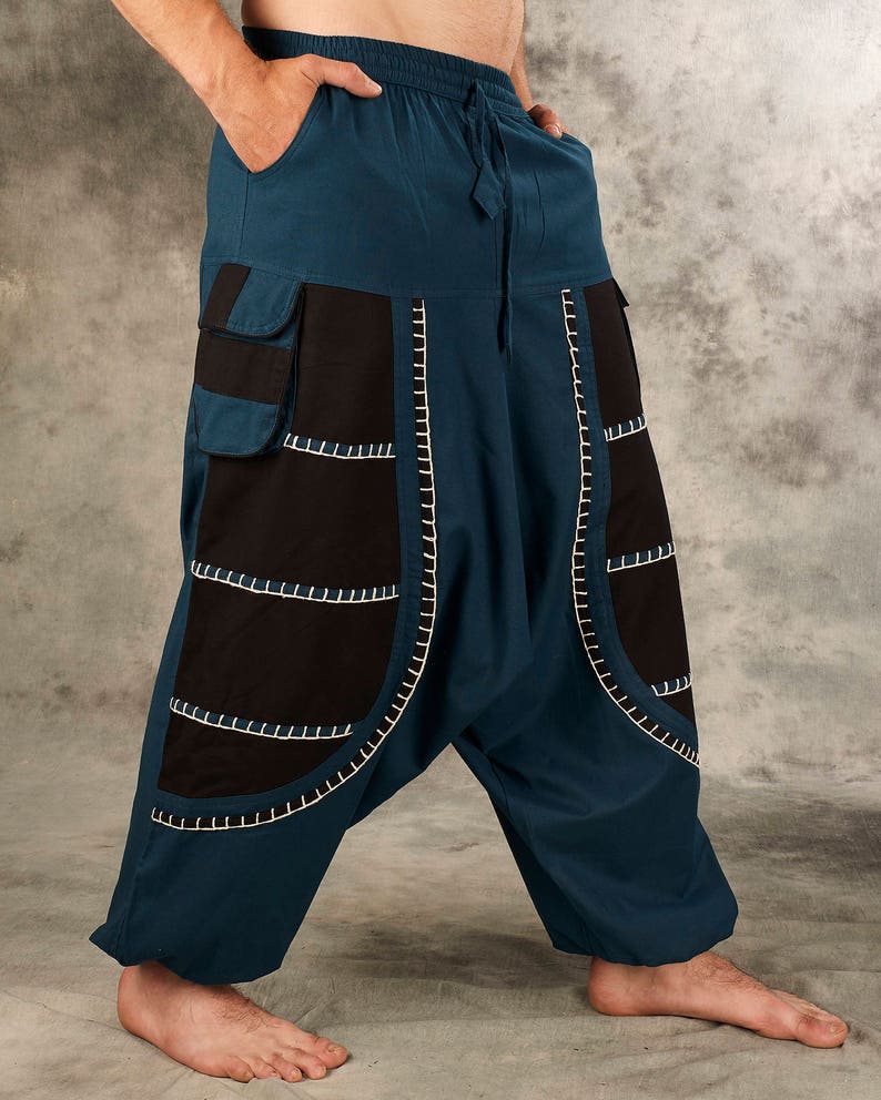 May include: Teal blue pants with black and white stitching detail. The pants have a loose, baggy fit and feature a drawstring waistband.