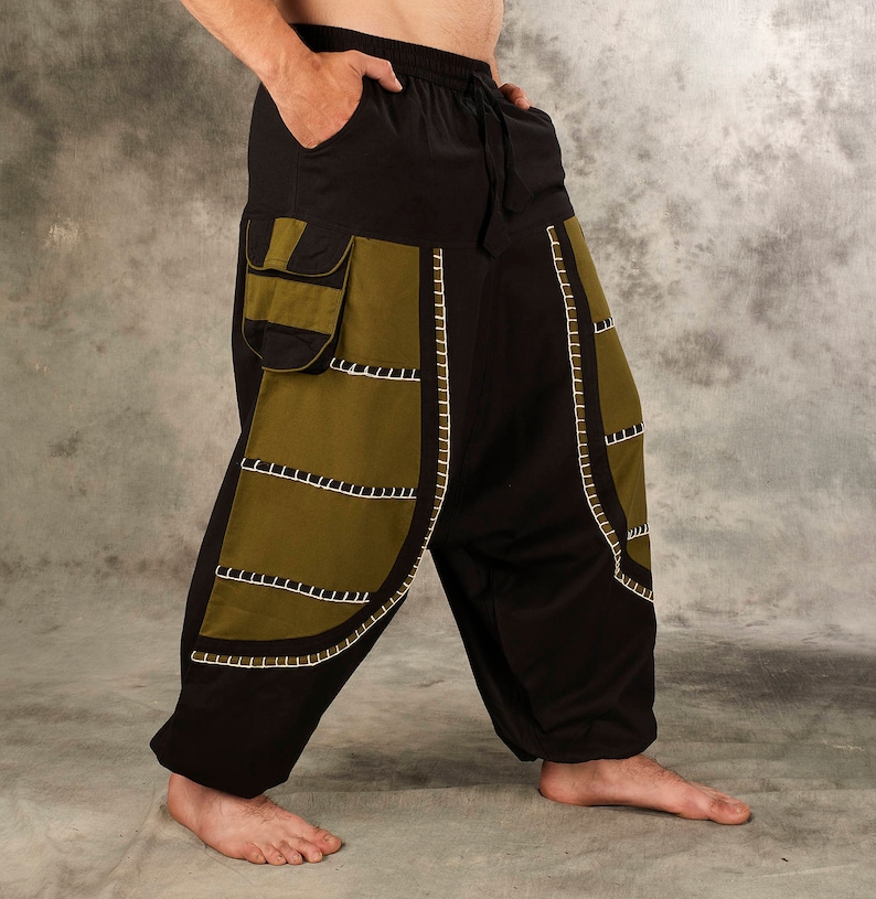 May include: Black and olive green pants with decorative stitching. The pants have a drawstring waist and a large pocket on the left side.